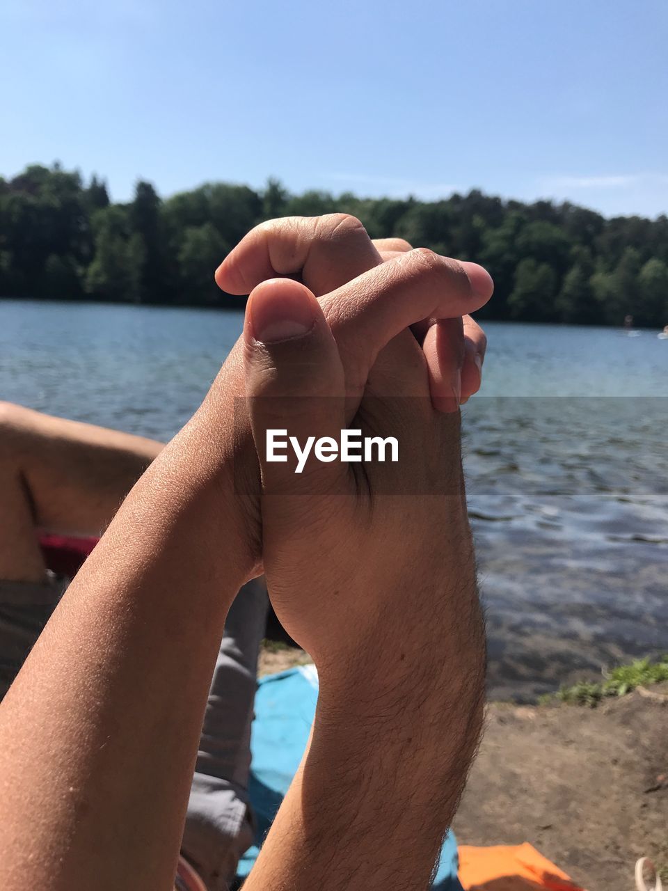 Cropped image of couple holding hands against lake