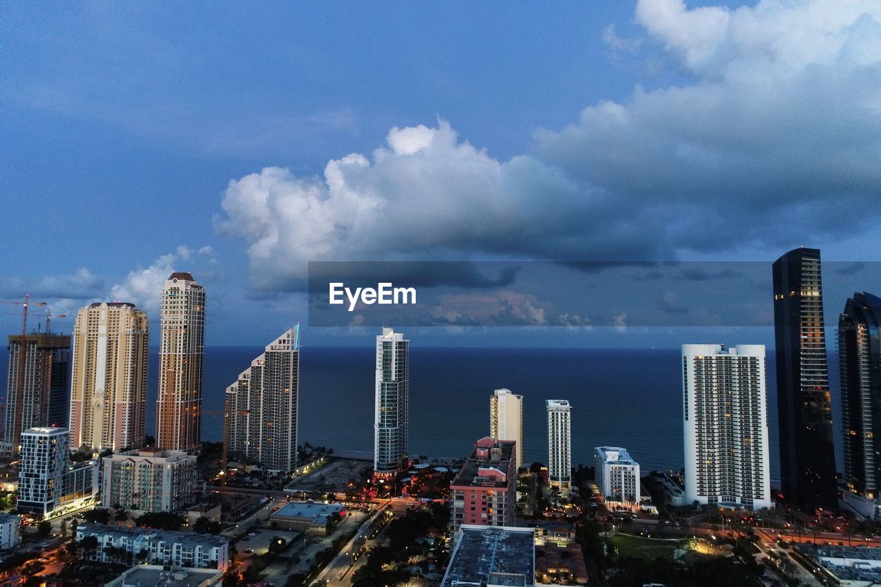 Modern buildings in city against cloudy sky