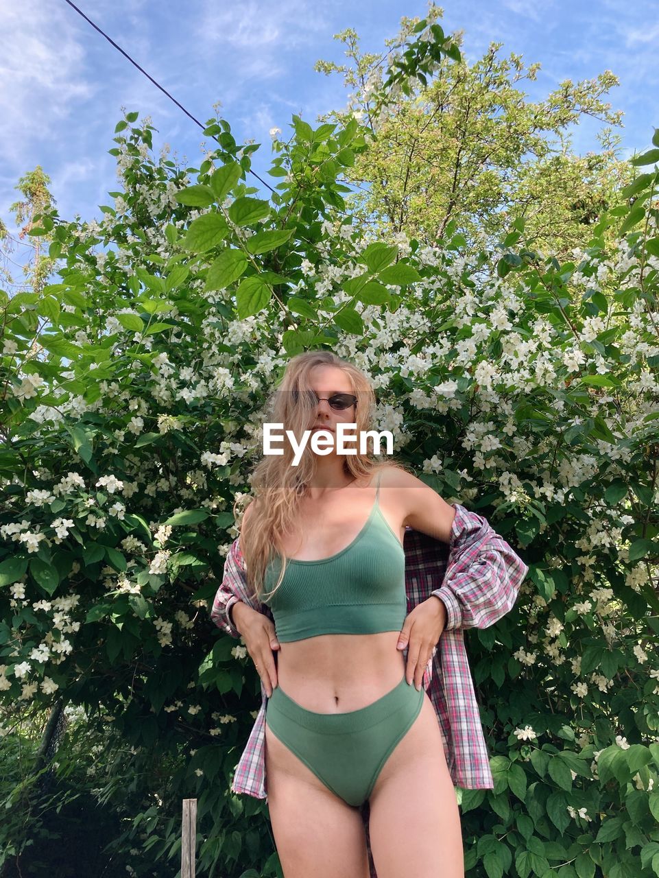 portrait of young woman in bikini standing against trees