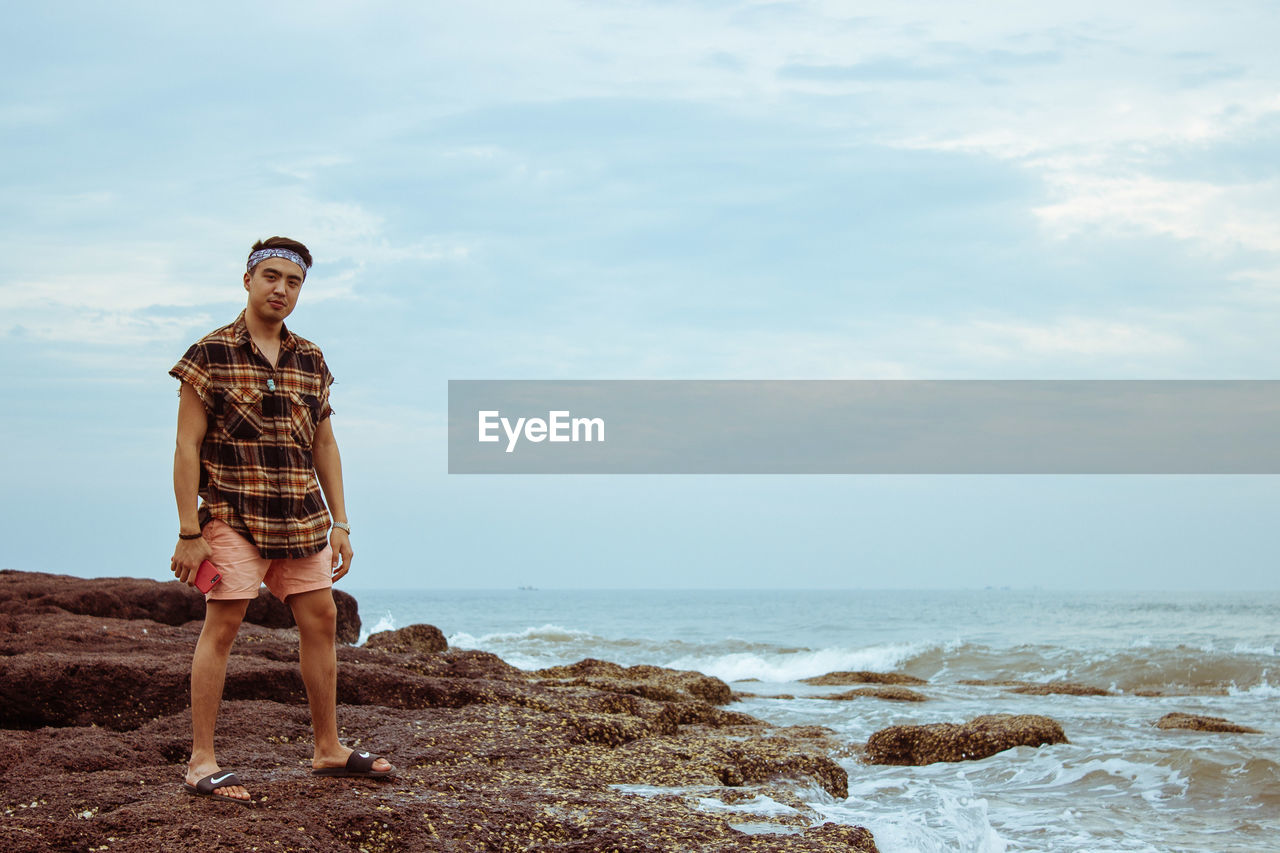 Full length of man standing at beach against sky