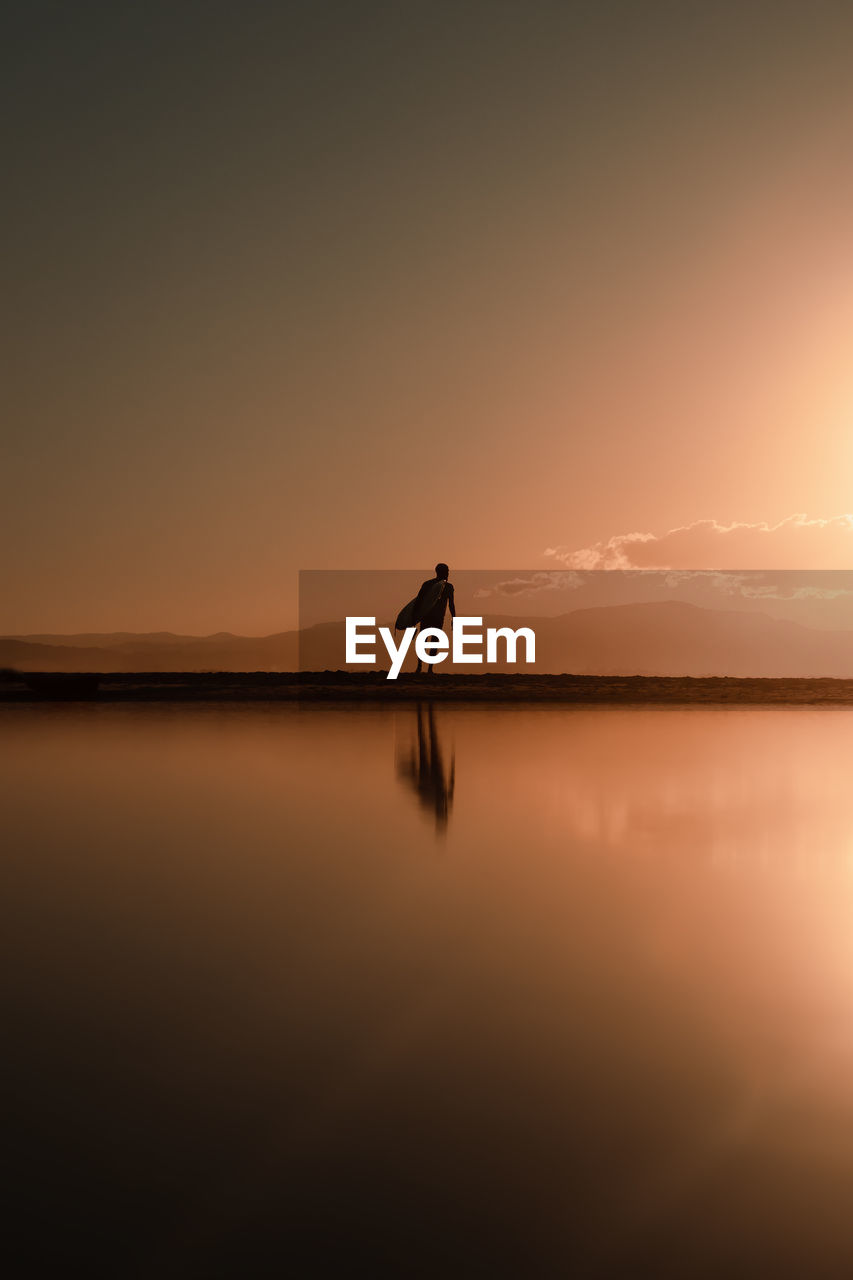 Silhouette man on beach against sky during sunset