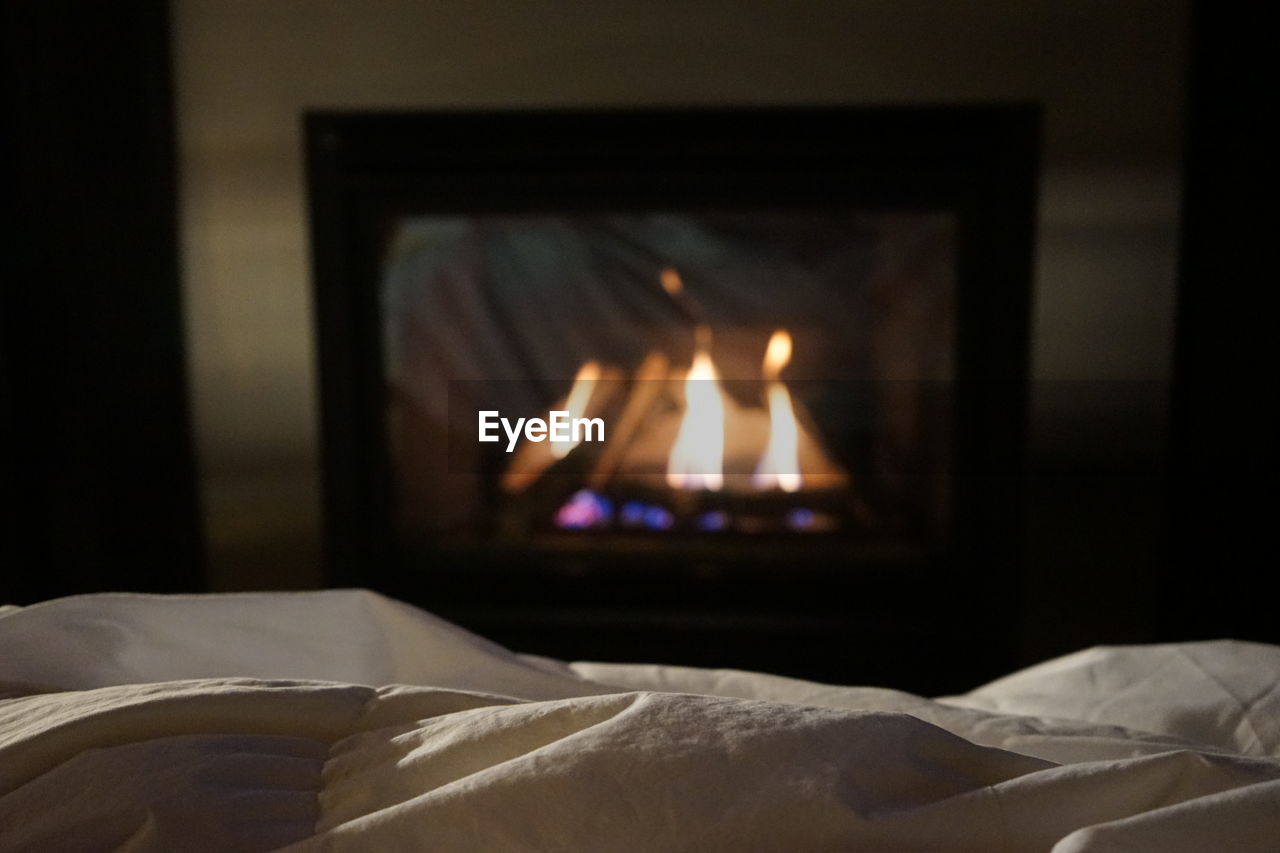 Close-up of sheet on bed with fireplace in background
