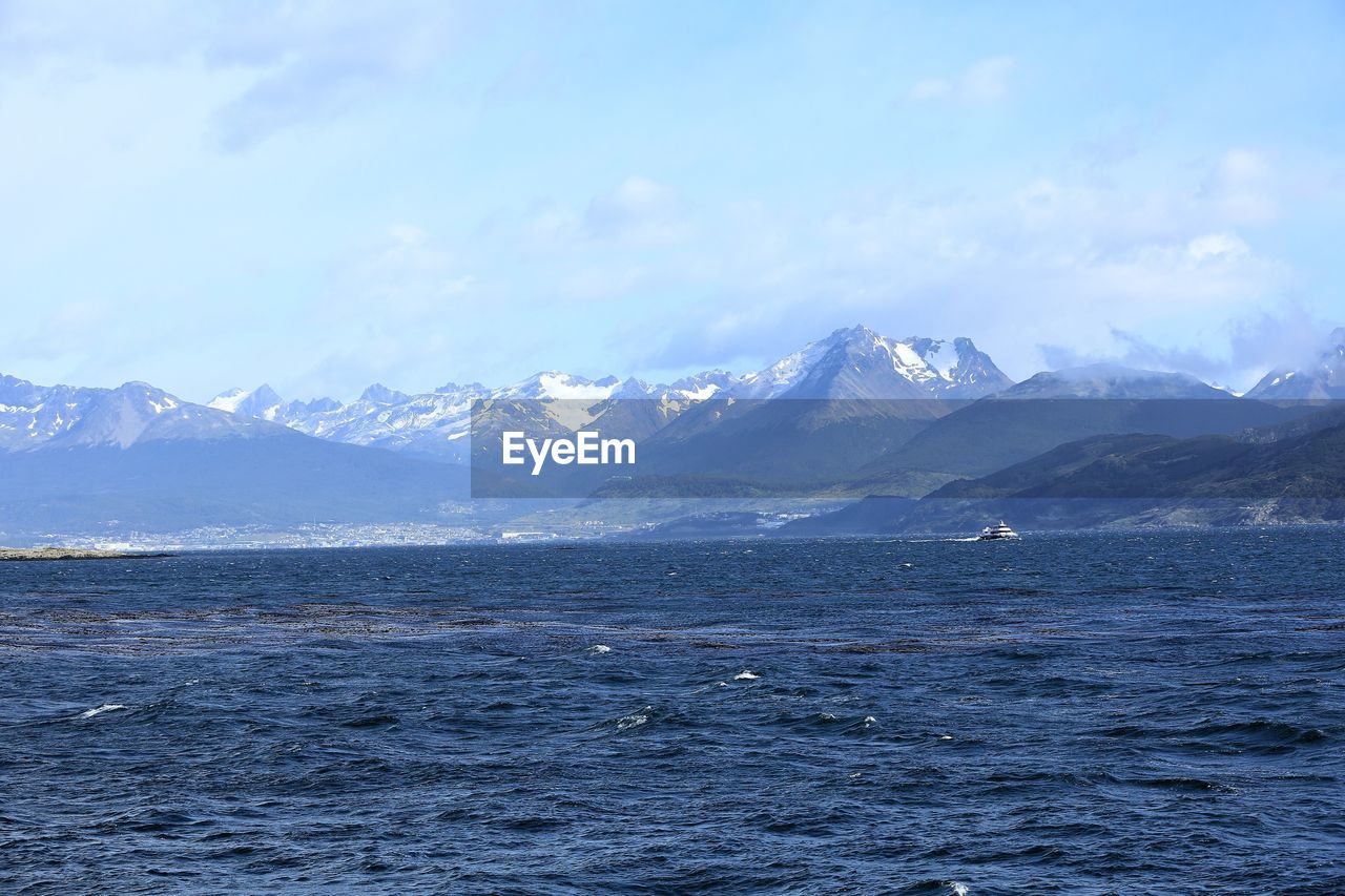 Scenic view of sea and snowcapped mountains against sky