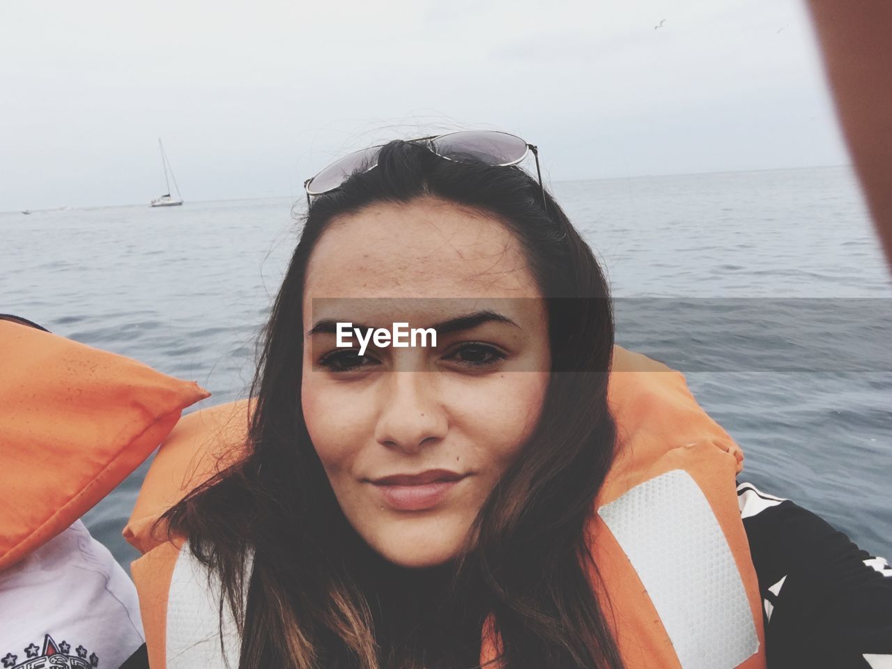 Smiling woman wearing life jacket against sea during foggy weather