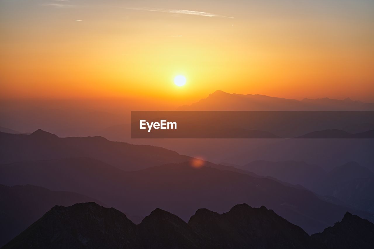 scenic view of mountains against orange sky during sunset