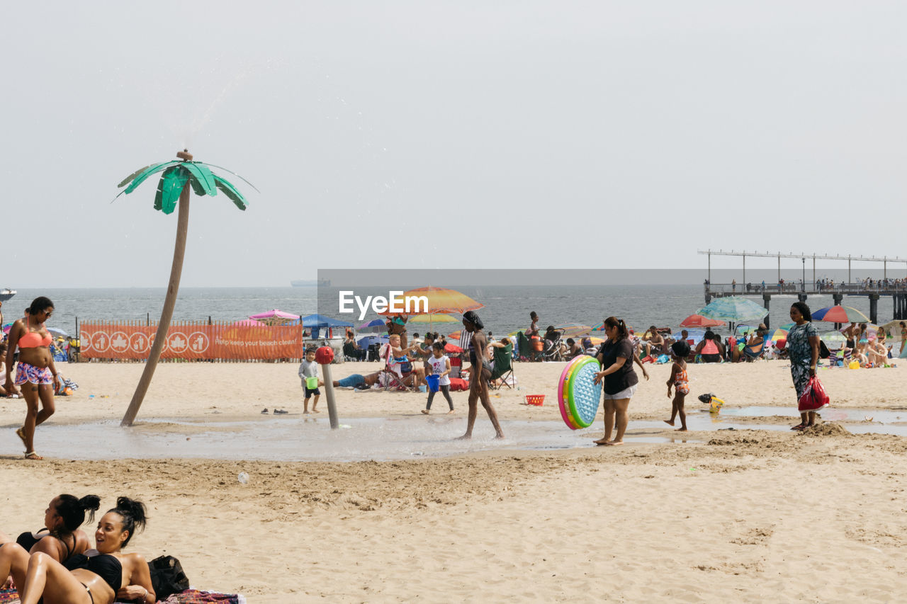 PEOPLE ON BEACH AGAINST CLEAR SKY