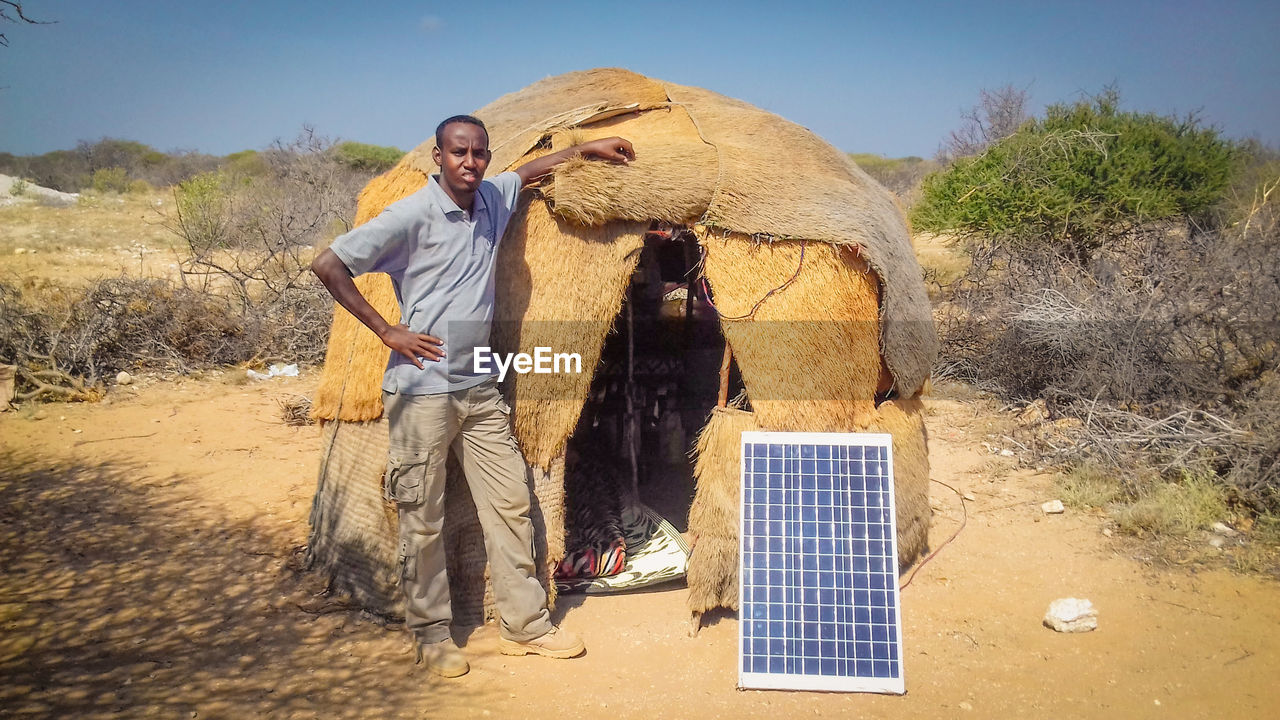 A young man standing next to a nomad house near hiiraan african villages