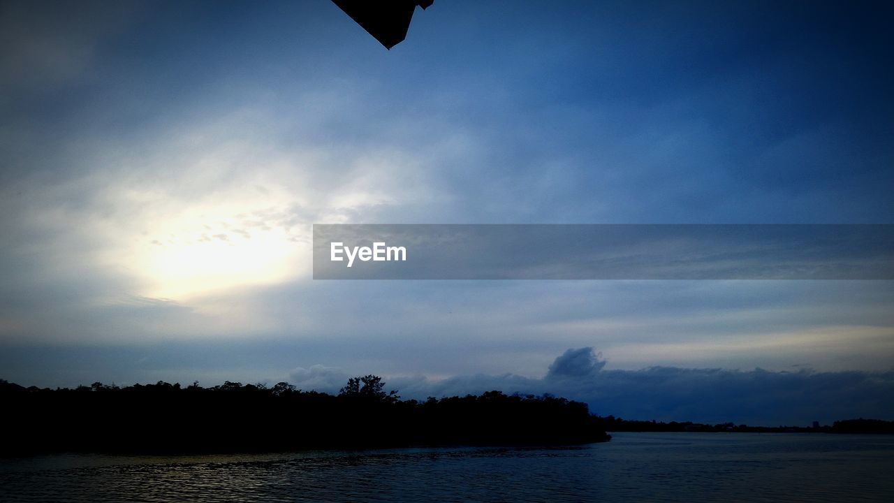 Scenic view of river against cloudy sky at sunset