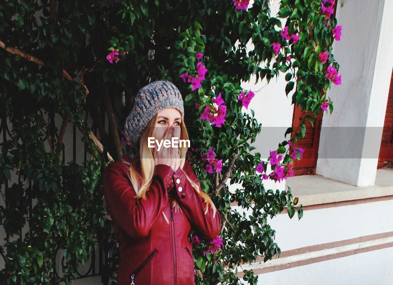 Surprised woman standing by pink flowering plants