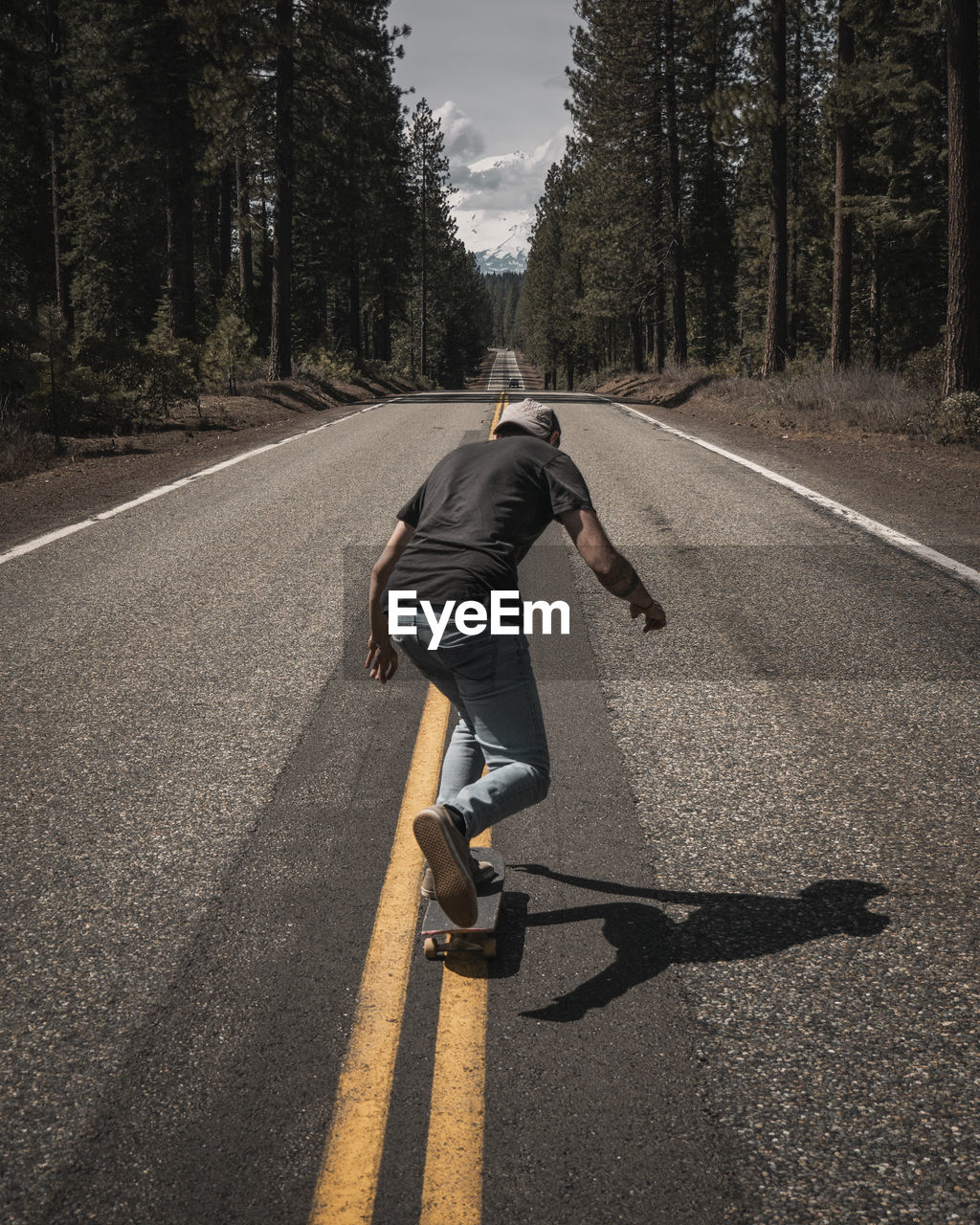 Rear view of man skateboarding on road