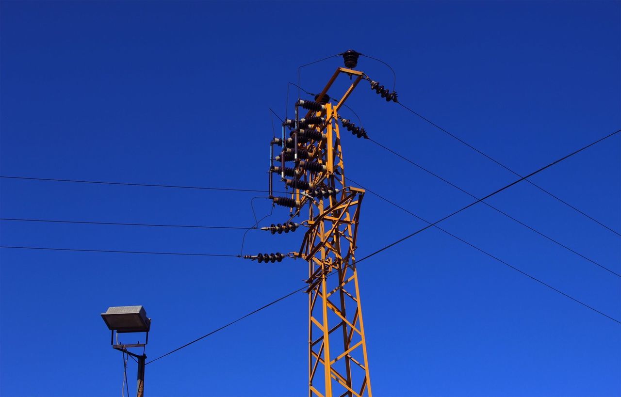 LOW ANGLE VIEW OF ELECTRICITY PYLONS AGAINST CLEAR BLUE SKY