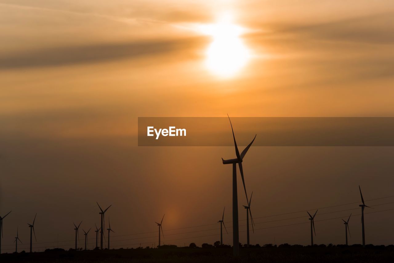 LOW ANGLE VIEW OF SILHOUETTE WINDMILLS AGAINST SKY DURING SUNSET