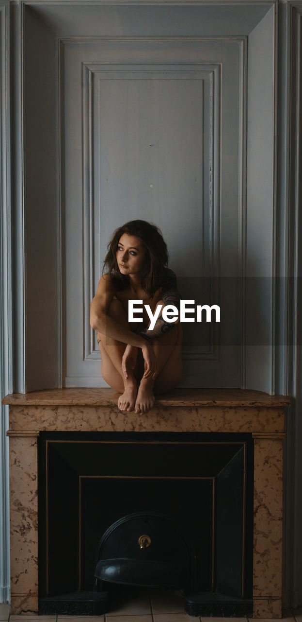 PORTRAIT OF YOUNG WOMAN SITTING AT HOME