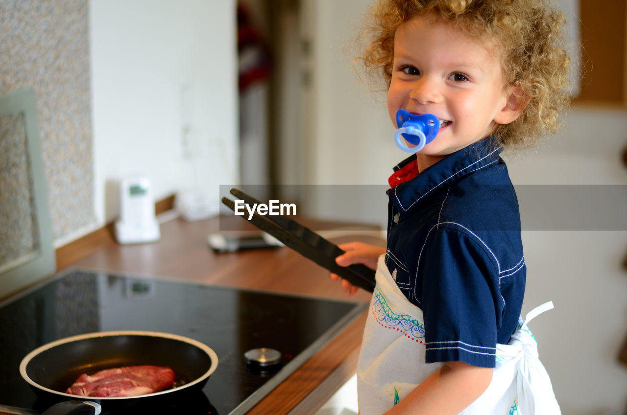 Portrait of smiling girl preparing food in kitchen at home