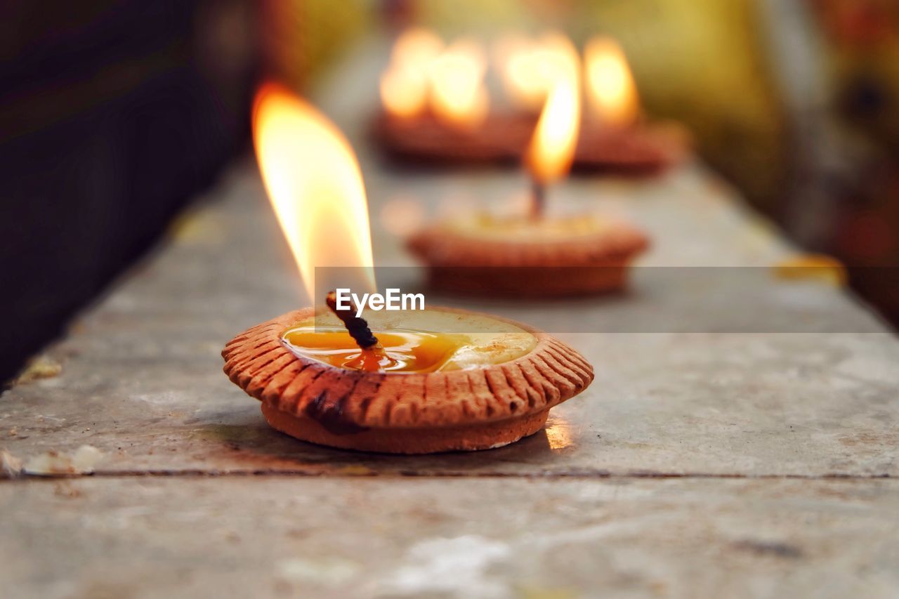 Close-up of burning diya on retaining wall