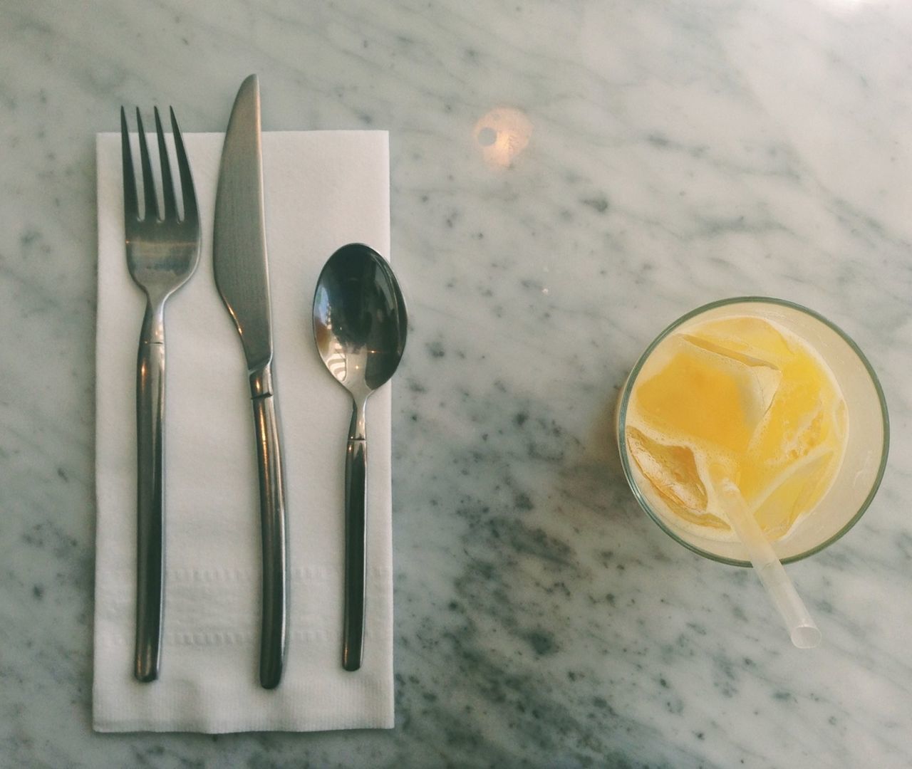 Directly above shot fresh orange juice with cutlery on marble