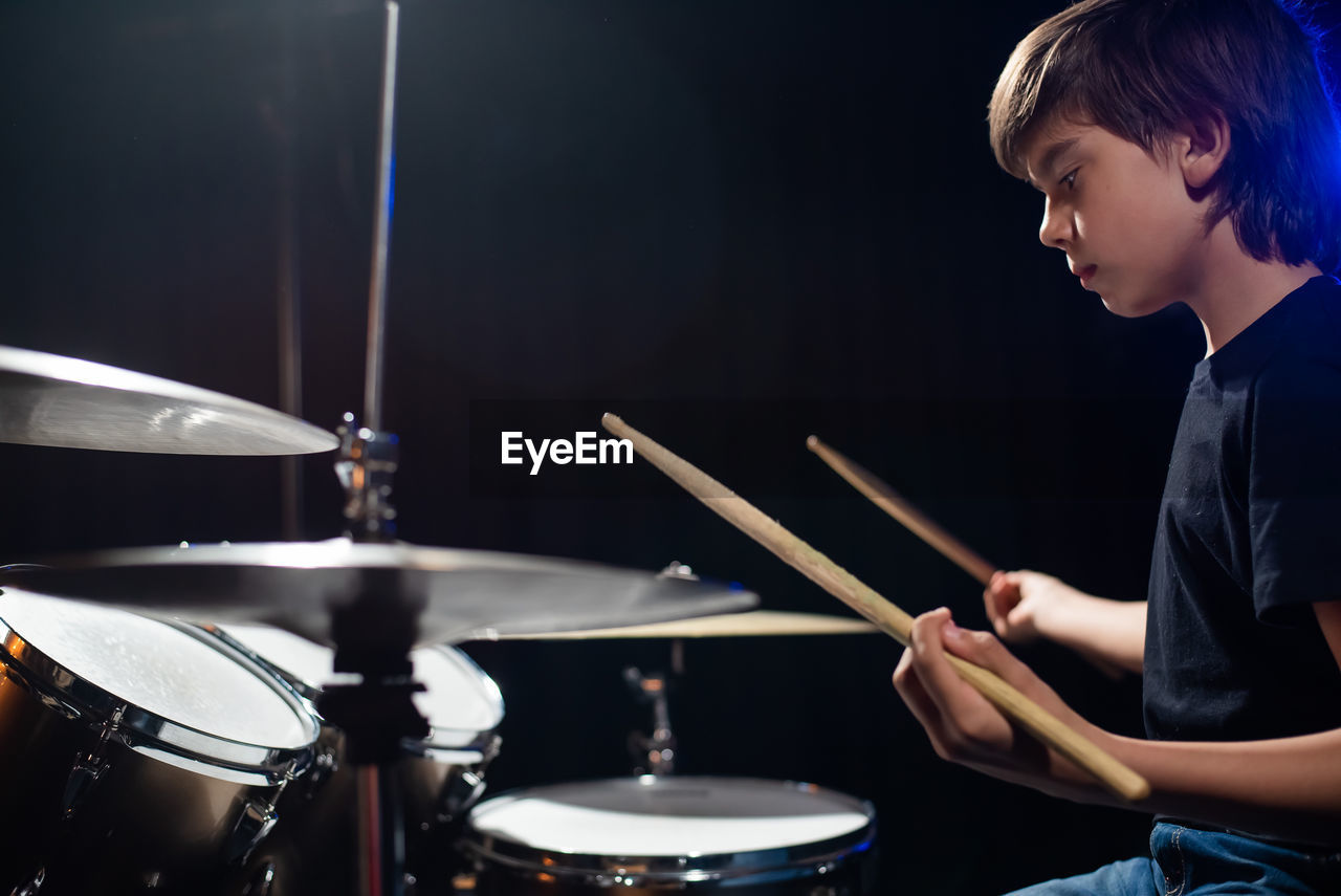 side view of man playing drum at home