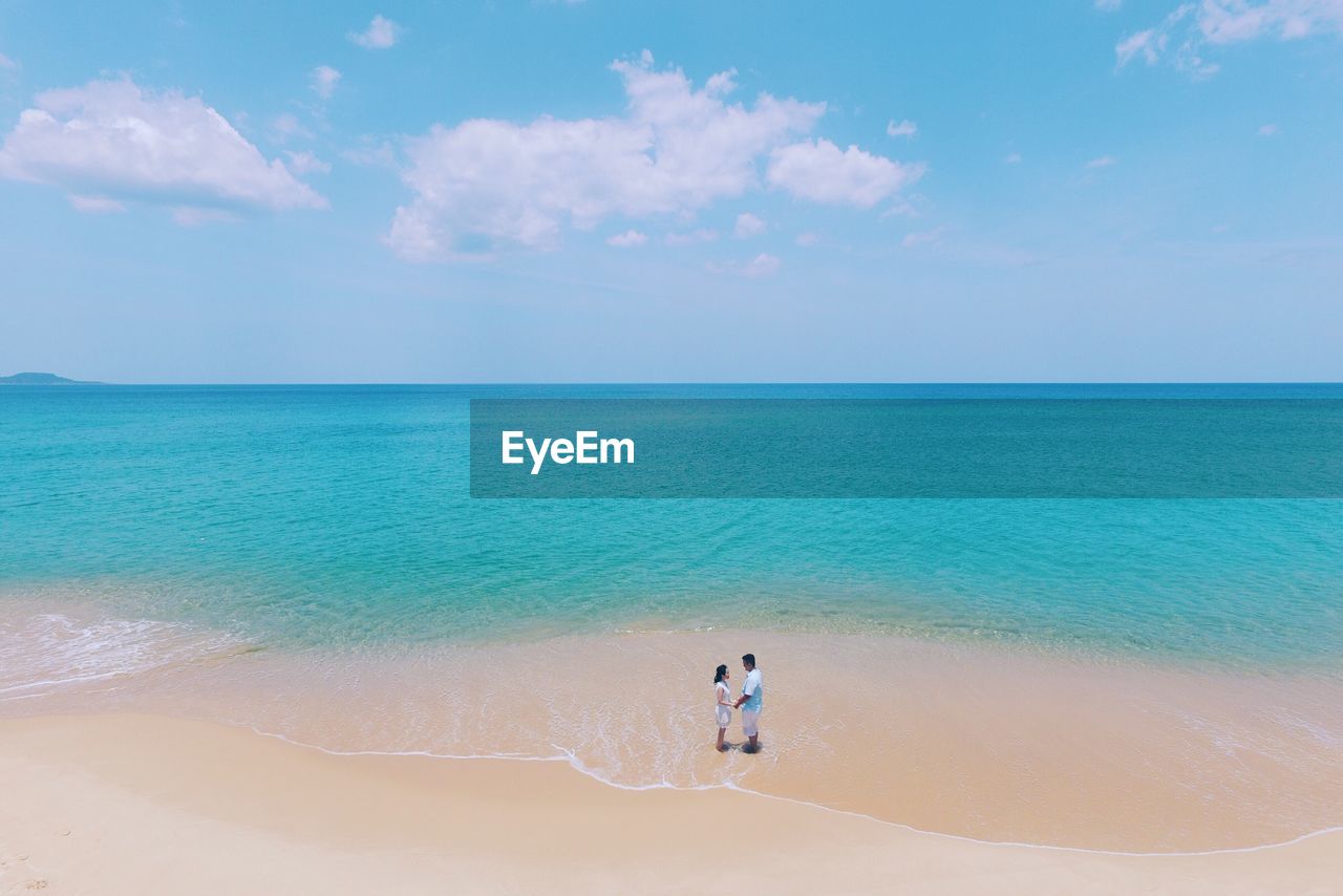 High angle view of couple standing at sandy beach