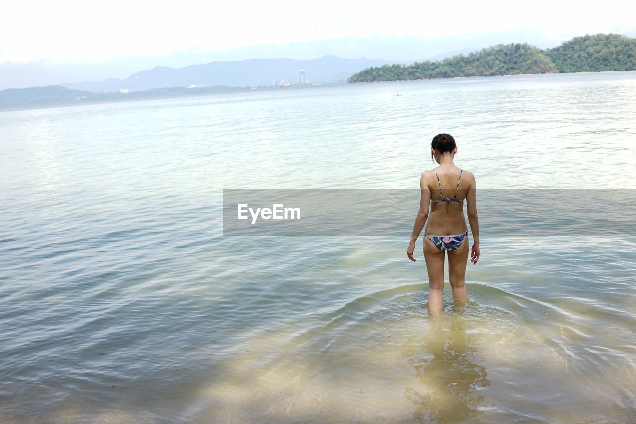Rear view of a bikini woman in calm sea