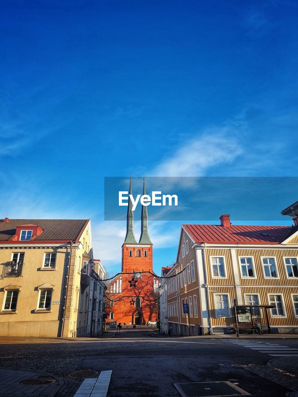 STREET BY BUILDINGS AGAINST BLUE SKY