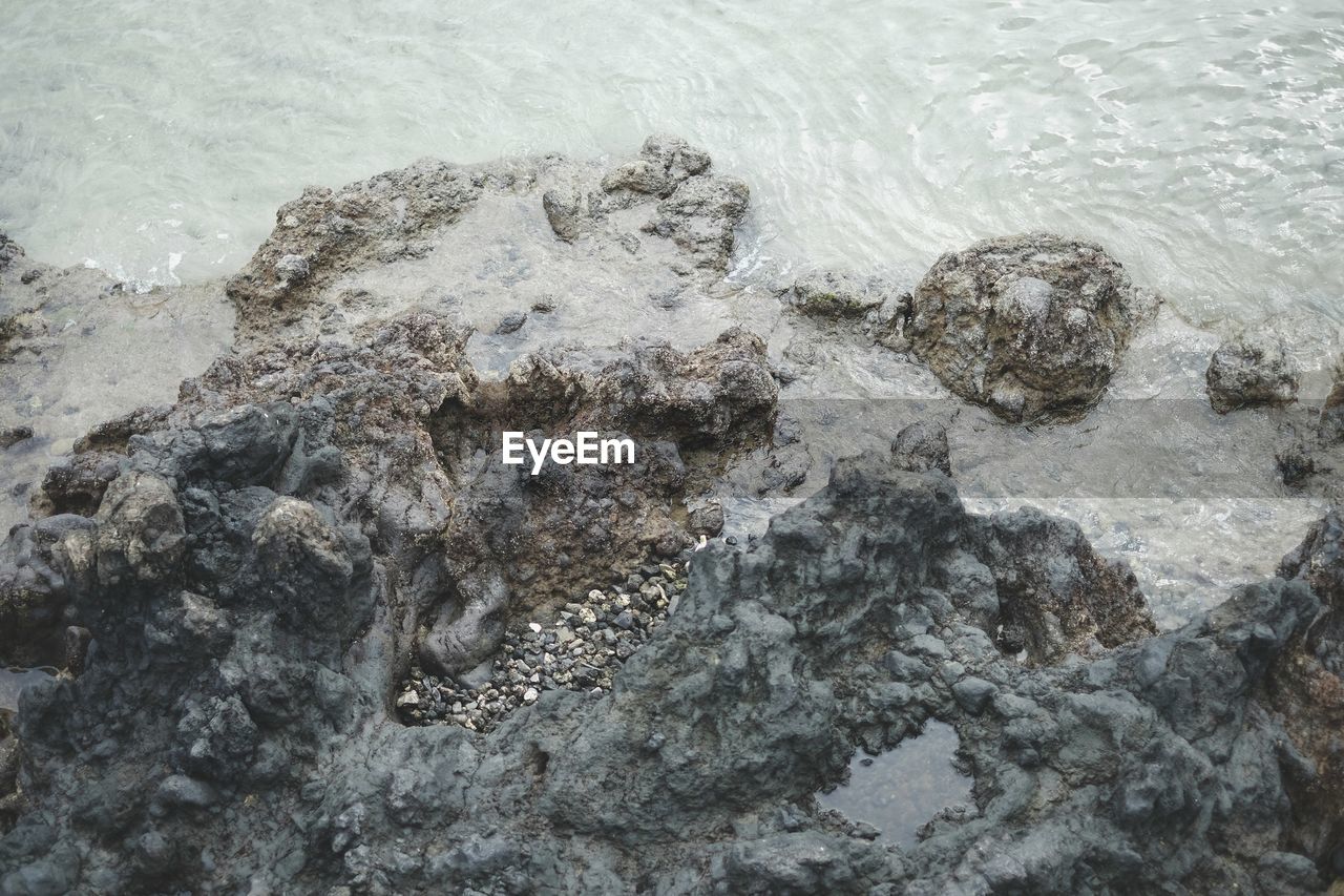 HIGH ANGLE VIEW OF ROCKS IN WATER