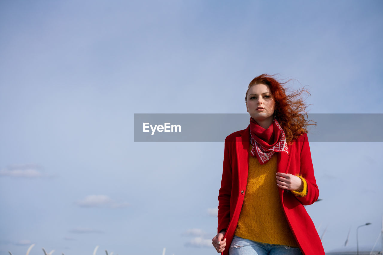 Portrait of smiling young woman standing against sky