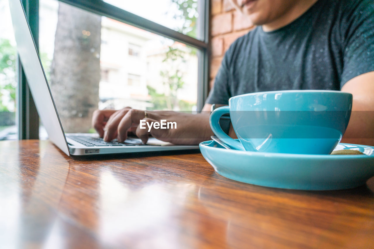 Midsection of man using laptop on table