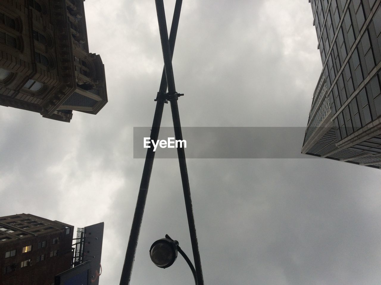 Directly below shot of street light and building against cloudy sky