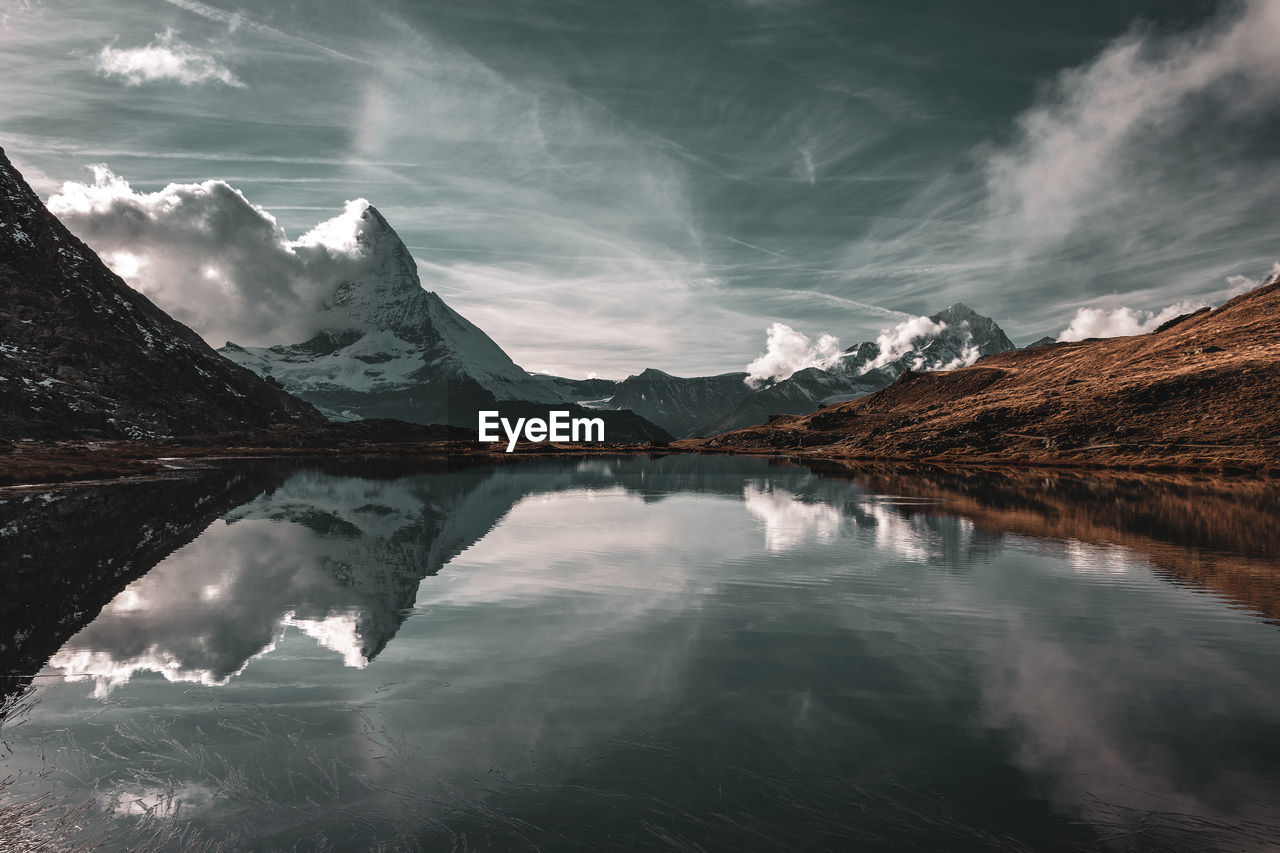 Scenic view of lake by mountains against sky