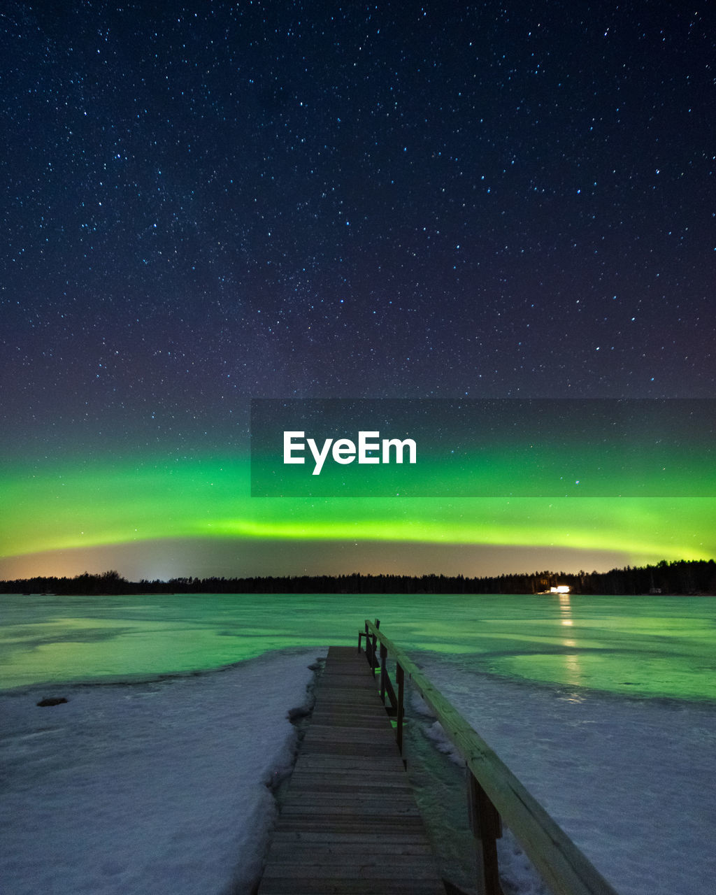 Wooden footbridge over sea against sky at night