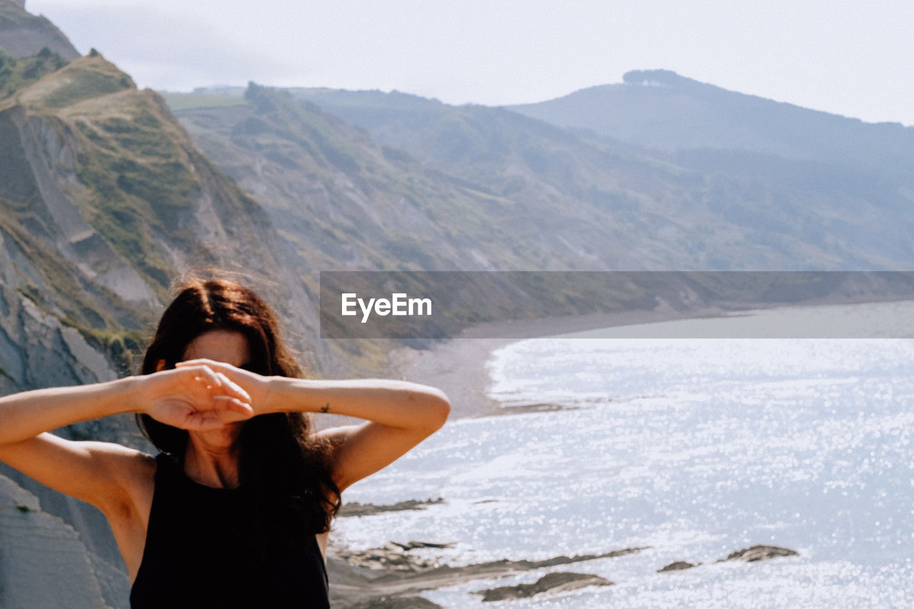 Rear view of woman with arms raised standing on snowcapped mountain