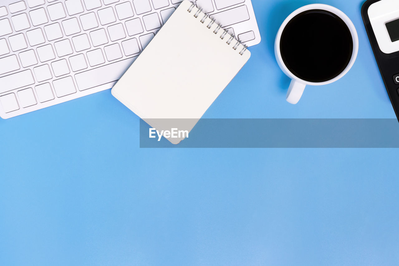 HIGH ANGLE VIEW OF COFFEE CUP AGAINST BLUE BACKGROUND