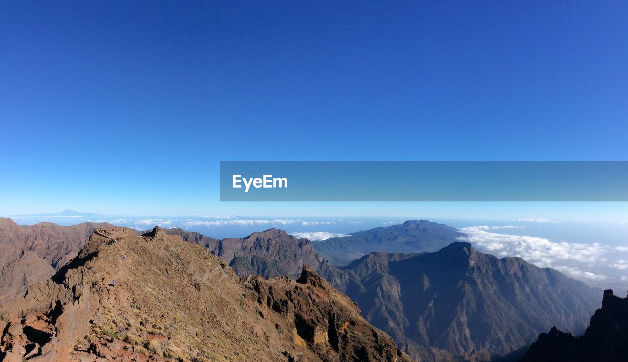 Scenic view of mountains against clear blue sky