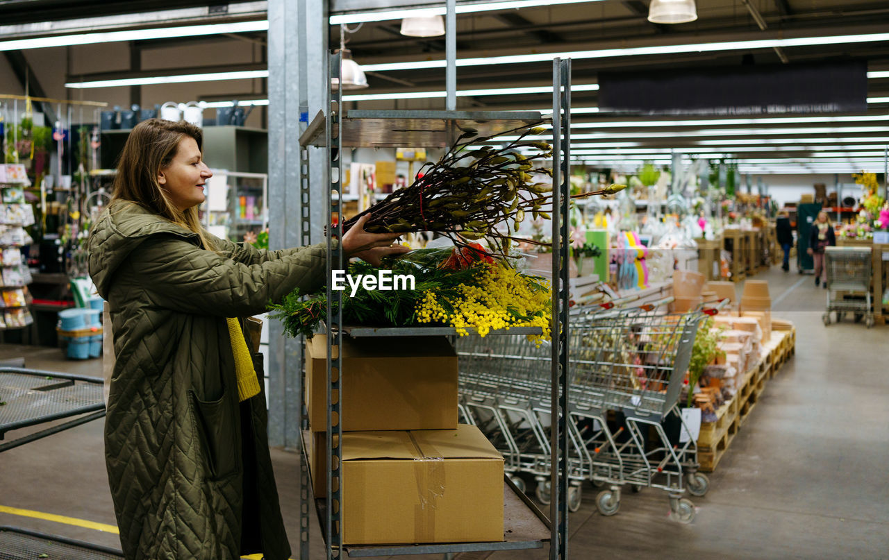 Girl stacks flowers on a shelf in a large flower shop