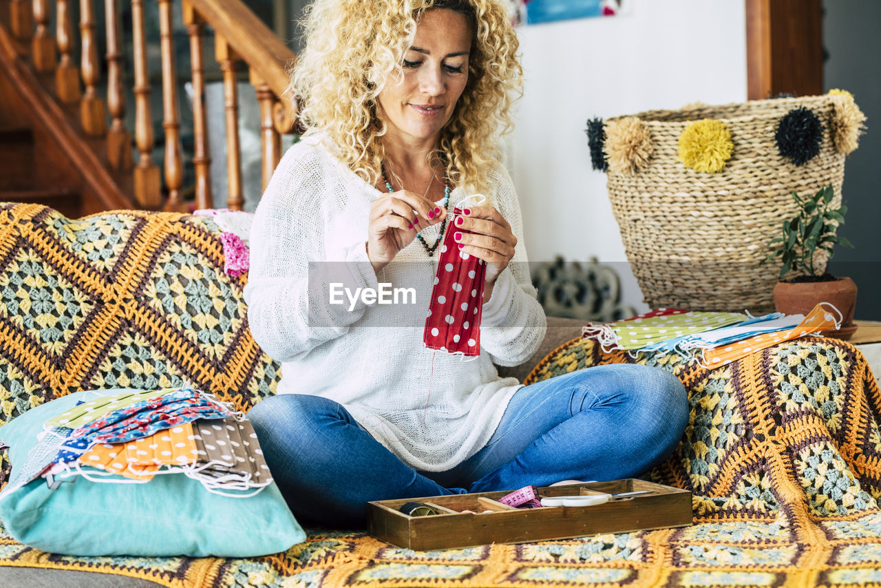 Woman stitching mask while sitting at home