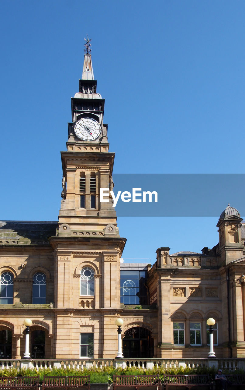 LOW ANGLE VIEW OF CLOCK TOWER AMIDST BUILDINGS AGAINST SKY