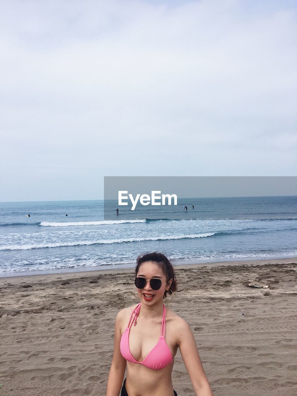 PORTRAIT OF YOUNG WOMAN IN SUNGLASSES ON BEACH