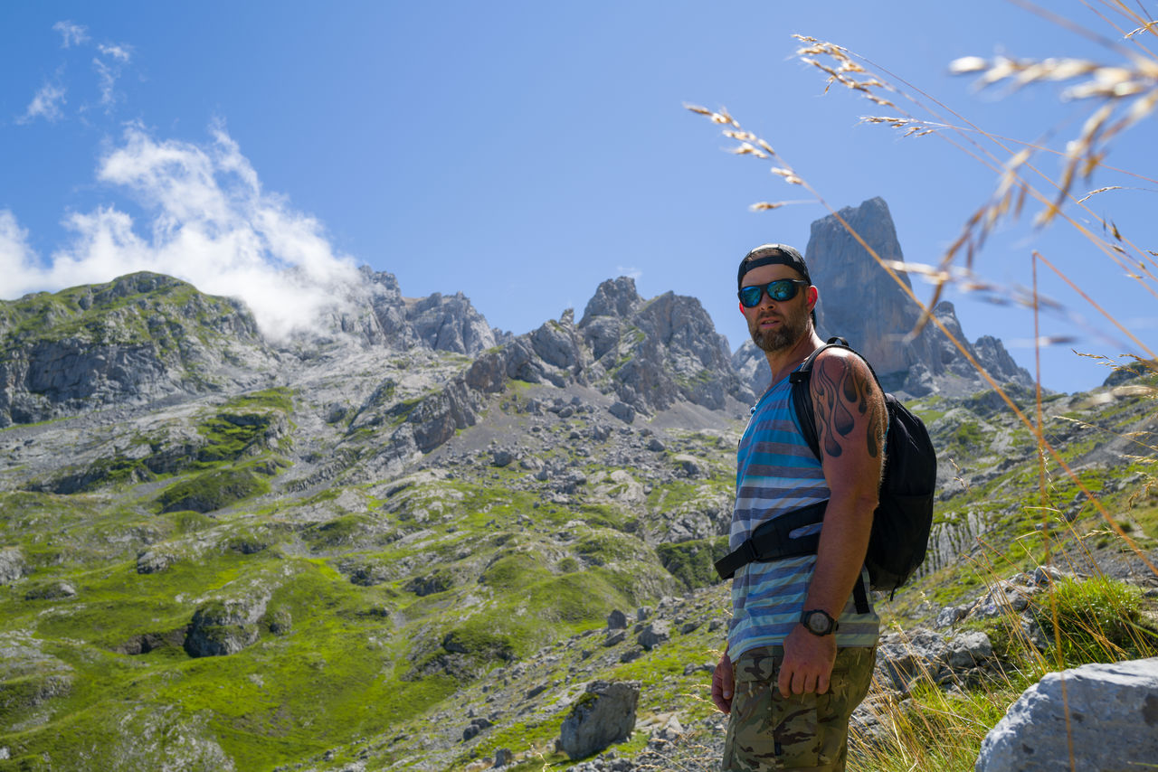 Male hiker standing outdoors looking at camera overlooking a mountain