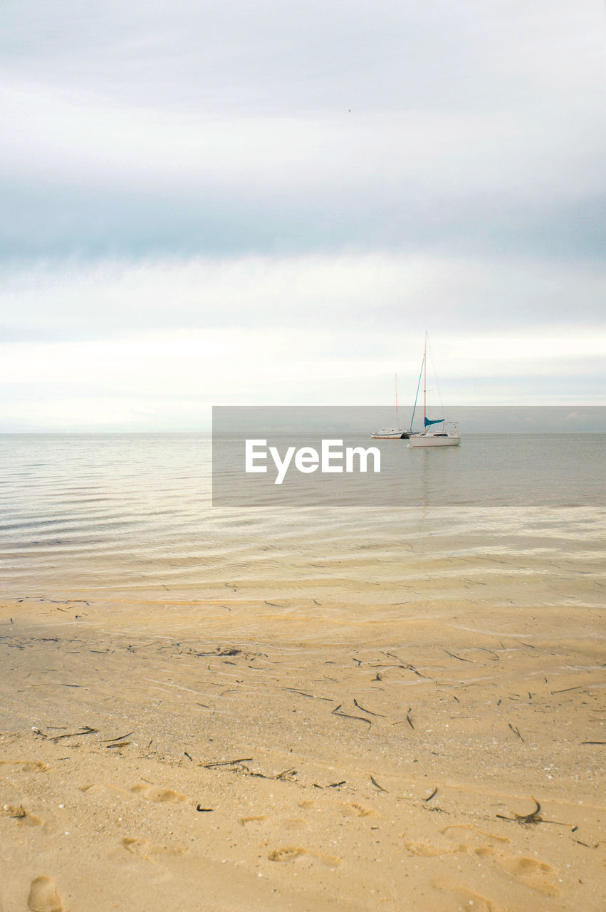 SAILBOAT ON BEACH AGAINST SKY