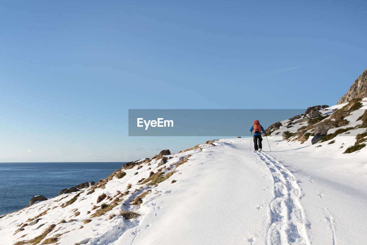 Rear view of man walking on snow covered landscape