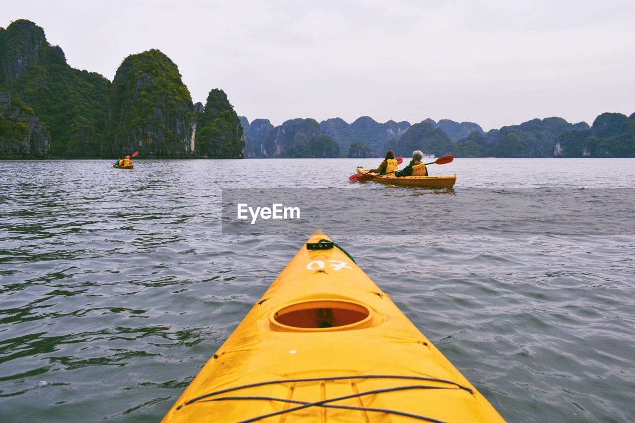 People kayaking in halong bay against clear sky