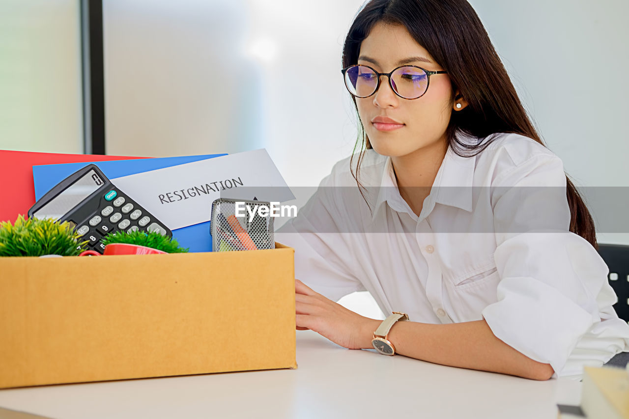 Woman with objects sitting at desk in office