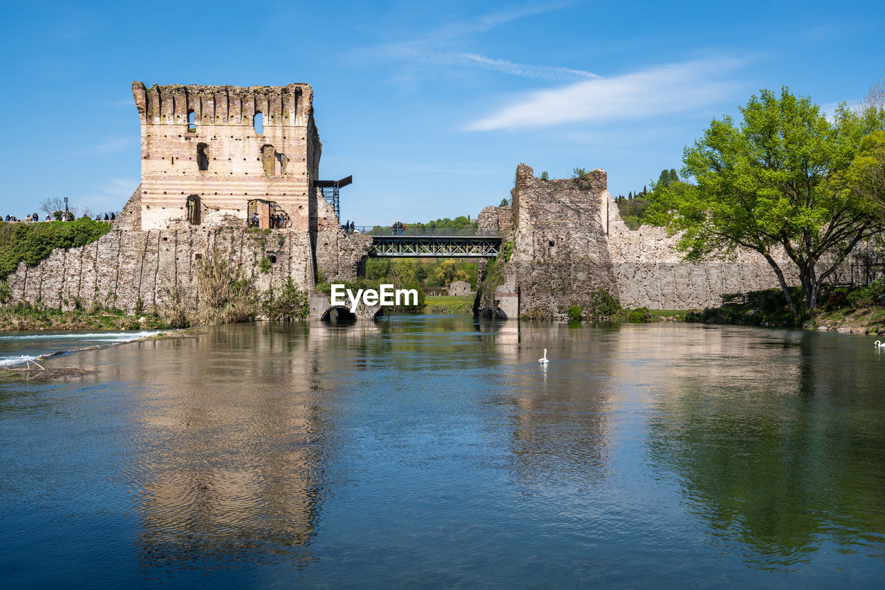 Ruins of visconti bridge reflecting into the water at borghetto sul mincio, italy