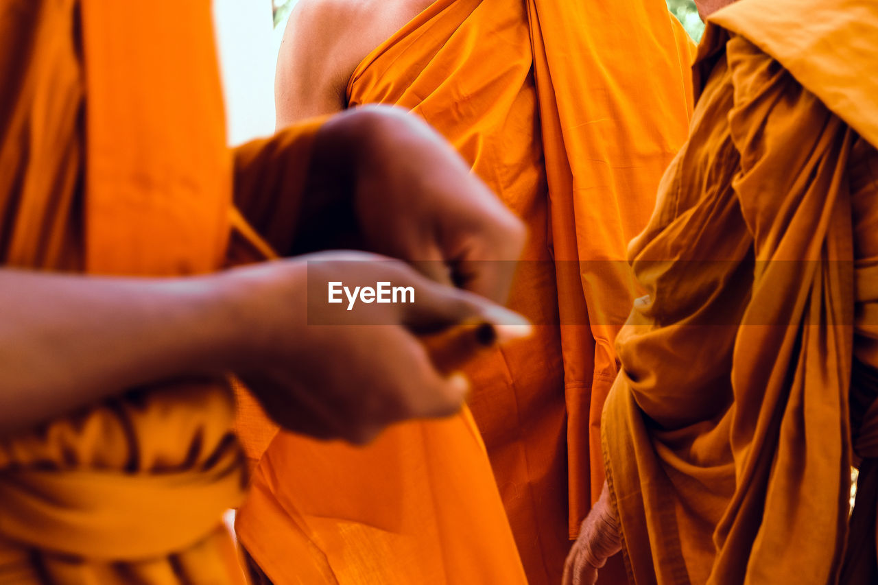 Midsection of monks wearing traditional clothing while standing outdoors