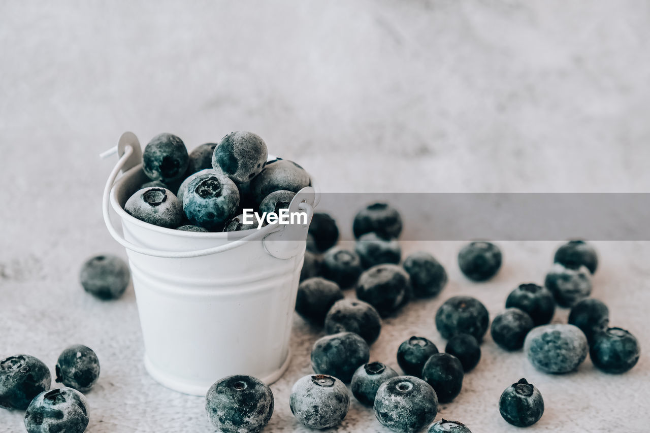 Frozen blueberries in small bucket on concrete background. healthy organic seasonal fruit 