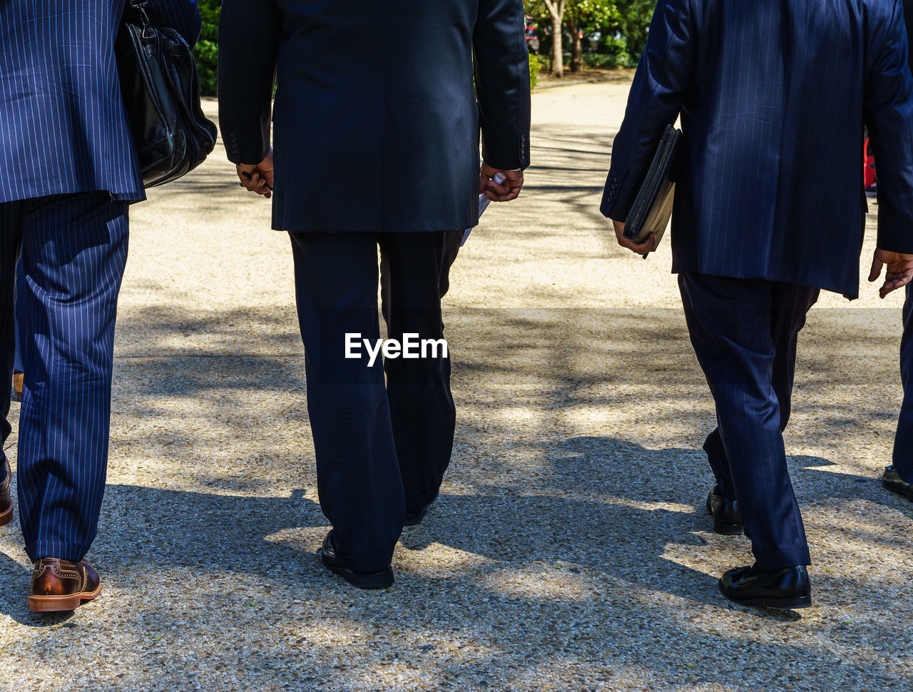 Low section view of three businessmen walking