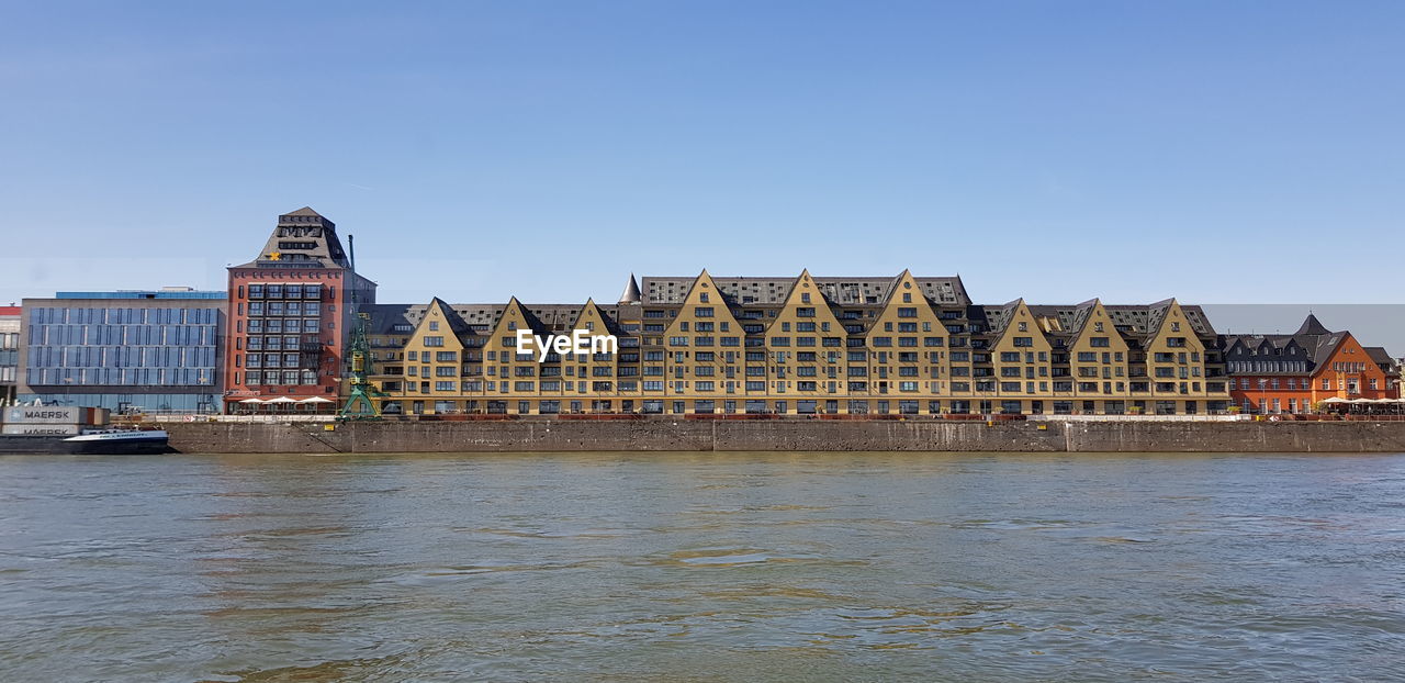 BUILDINGS BY RIVER AGAINST CLEAR SKY