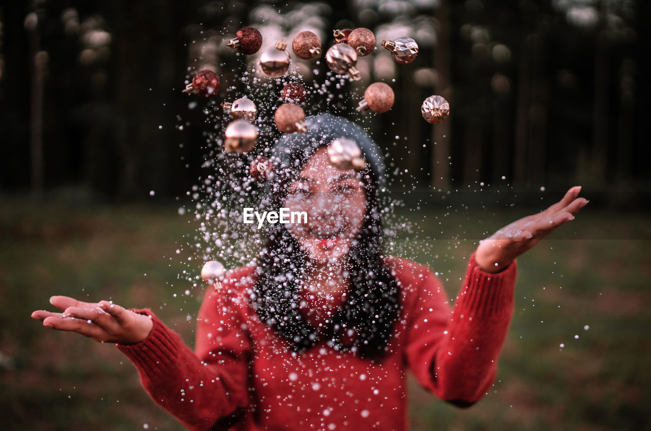 Young woman throwing confetti and christmas ornaments in air