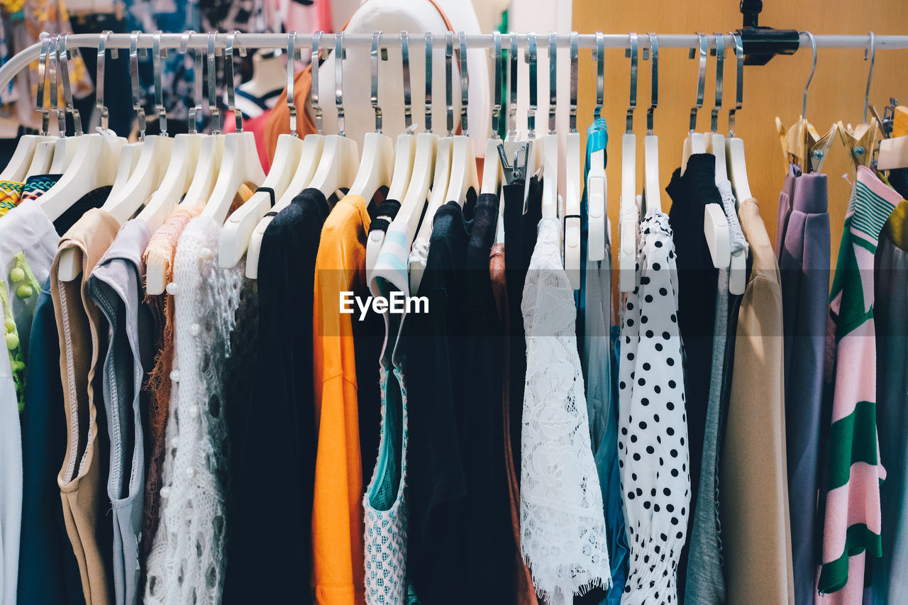 View of various clothes hanging for sale at market