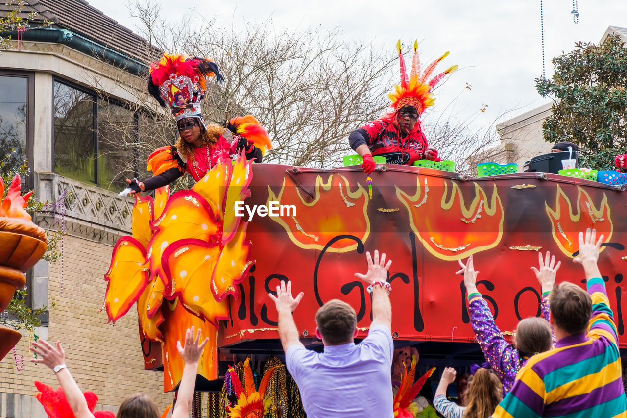 group of people, celebration, event, tradition, men, carnival, crowd, architecture, adult, chinese new year, festival, women, large group of people, dancing, city, arts culture and entertainment, traditional festival, multi colored, day, outdoors, person, nature, lifestyles, togetherness, building exterior, street